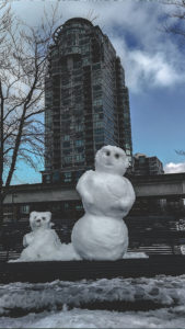 Schneemänner auf Parkbank vor Hochhaus in Vancouver