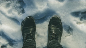 Blick von oben auf schwarze Stiefel im Schnee